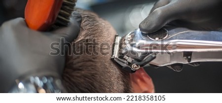 Modern urban hairdresser cut hair with hair trimmer in professional hairdressing salon and studio. Close-up detail view