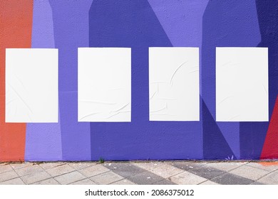 Modern urban street scene with colorful geometrical wall and four white glued wrinkled poster templates. Modern mockup for design presentation. Creative purple orange urban city background. 