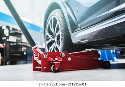 Modern Vehicle and the Floor Jack Lift Vehicle Servicing and Maintenance Inside Auto Service Center. - Shutterstock ID 2112216011