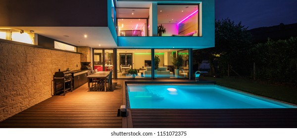 Moderne Villa mit farbenfrohen Lichtern am Abend. Niemand drinnen