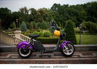 Modern Violet Electro Electric Scooter And Yellow Helmet Parking In Park