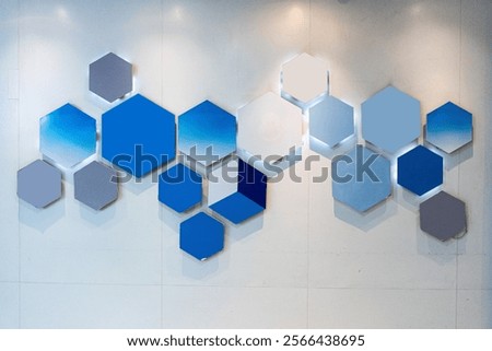 A modern wall design featuring a pattern of blue and gray hexagonal shapes, some with subtle lighting.
