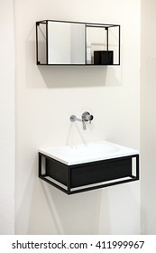 Modern Wall-mounted Black And White Sink Or Hand Basin With Small Cupboard Above On A White Interior Wall In A Bathroom Of A House