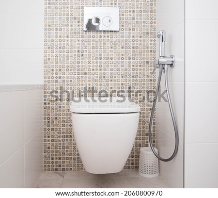Modern wall-mounted toilet with shower for private spaces. White and clean bathroom, background