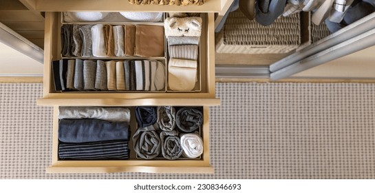 Modern wardrobe with stylish women's clothing. Drawer with underwear, t-shirts, socks and shorts. The concept of storage and order. Top view.