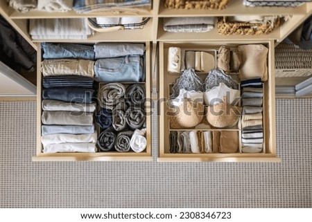 Modern wardrobe with stylish women's clothing. Drawer with underwear, t-shirts, socks and shorts. The concept of storage and tidiness order.