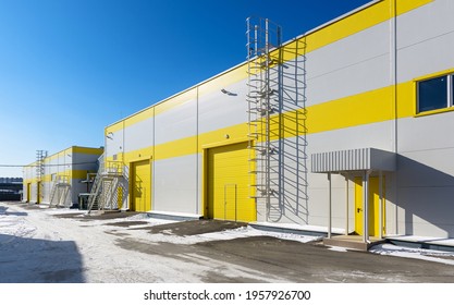 Modern Warehouse Exterior In Winter, Panorama Of Large Yellow Storehouse Or Mechanic Shop. Big New Commercial Industrial Buildings. Concept Of Contemporary Warehouse, Logistic, Repair And Transport.