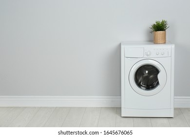 Modern washing machine with houseplant near white wall, space for text. Laundry day - Shutterstock ID 1645676065