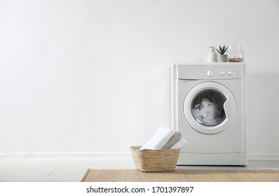 Modern washing machine and laundry basket near white wall indoors, space for text. Bathroom interior - Powered by Shutterstock