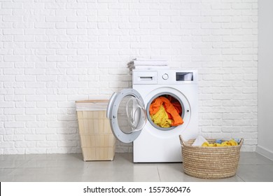 Modern washing machine with laundry near white brick wall - Shutterstock ID 1557360476