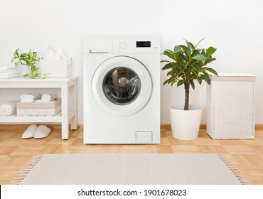 Moderne Waschmaschine, Handtücher und verwandte Gegenstände im Waschraum
