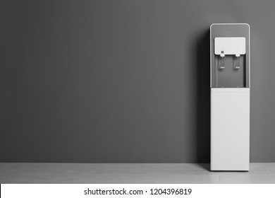 Modern Water Cooler Against Gray Wall With Space For Text