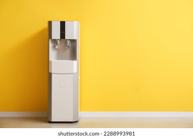 Modern water cooler near yellow wall