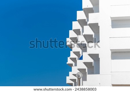 Modern white building balconies against a clear blue sky