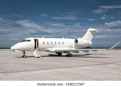 Modern white corporate business jet with a lowered gangway door at the airport apron