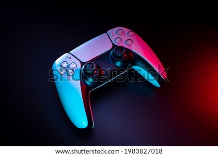 Modern white gamepad illuminated in red and blue. Game controller for video games and e-sports on a dark background.