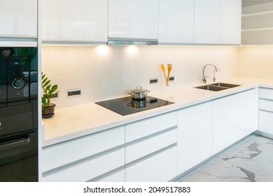 Modern White Kitchen With Granite Countertops And White Cabinet. Have Modern Black Induction Hob, Cooker, Built-in Hood, Sink ,tap Water In Kitchen. White Tone And Clean Kitchen