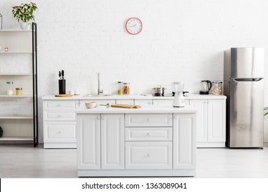 modern white kitchen with table and kitchenware and fridge 
