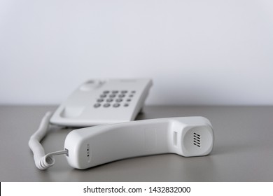 Modern White Landline Office Phone With A Hook. Technical Support Concept. No Answer. Closeup White Phone , Office Phone On The Desk. 