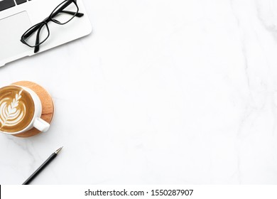 Modern White Marble Office Desk Table With Laptop Computer, Cup Of Coffee And Supplies. Top View With Copy Space, Flat Lay.