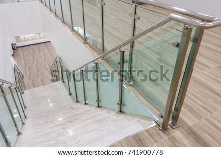 Modern white marble stairs with steel and glass railing in a new modern building.