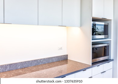 Modern White Minimalist Kitchen Features Cabinets With Granite Countertop And Microwave Toaster With Empty Space In Office Or Home