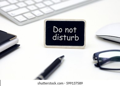 Modern White Office Desk Table With Laptop, Smartphone, Pen , Notebook And Mouse . Blackboard  With Do Not Disturb Text In The Middle. 
