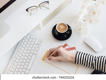 Modern white office desk table with keyboard, mouse, glasses, orchid, notebook and cup of coffee. Top view, flat lay.