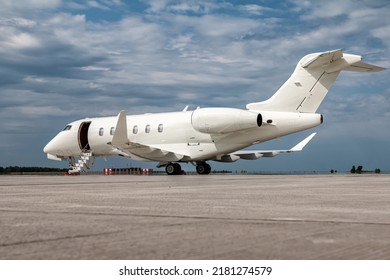 Modern white private jet with an opened gangway door at the airport apron