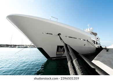 Modern, white and spotless superyacht at dock in a port in the Greeece, Mediterranean sea, with black fenders, dock lines and a sunny day  - Powered by Shutterstock