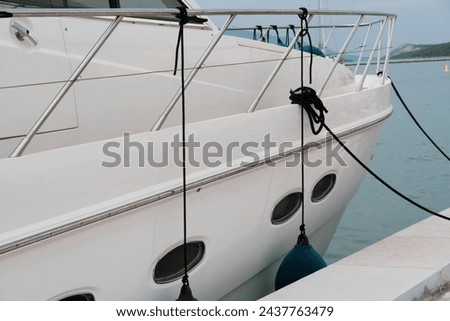 Modern white yacht anchored in European marina. Luxury holiday boating. Wealthy lifestyle. Boat fender on motorboat in harbor in daylight. Mediterranean dock. Rope. Ship in port. Money. Sailboat. Sea.