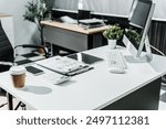 A modern, white-colored business office with a wooden desk, calculator, desktop computer, and a black leather chair. The executive office features private office furniture for the chief of staff.