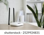 Modern wi-fi router on desk in office, closeup