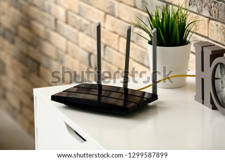 Modern wi-fi router on light commode near brick wall