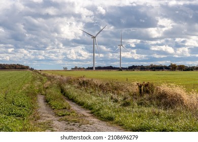 Modern Windmills Against Cloudy Sky, On Farm Field In Ontario, Canada.