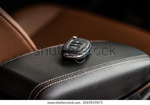 Modern wireless car key
on darl leather in car interior. Remote control key in vehicle
close up view.
