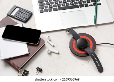 Modern wireless charger pad, different gadgets and notebooks on light background - Shutterstock ID 2169368969