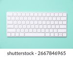 Modern wireless computer keyboard on turquoise background, top view