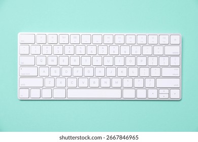 Modern wireless computer keyboard on turquoise background, top view
