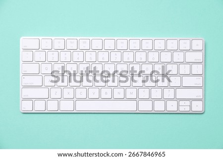 Modern wireless computer keyboard on turquoise background, top view