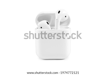 Modern wireless earbuds headphones lying in a charging case isolated on white background. 