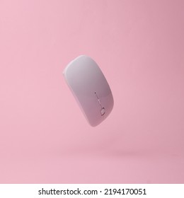 Modern wireless pc mouse flying in antigravity on pink background with shadow. Levitation object in the air. Computer techologies concept. Creative minimal layout