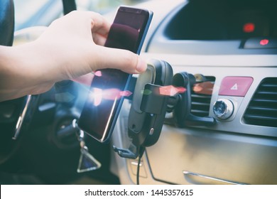 Modern Wireless Smartphone Charging In A Car With A Hand Putting A Phone On It. Dashboard In Background. 