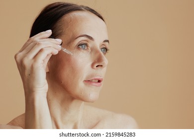 Modern Woman With Cosmetic Elixir Against Beige Background.