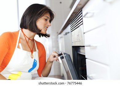 Modern Woman Looking Inside The Kitchen Oven