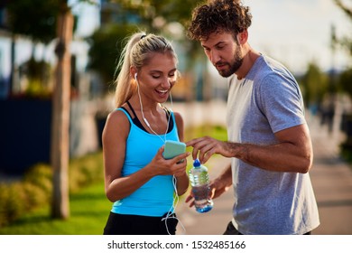 Modern woman and man jogging / exercising in urban surroundings and using cellphone at a pause / break. - Shutterstock ID 1532485166
