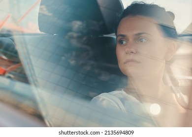 Modern Woman Sitting In Rear Seat Of Car On Road Trip Relaxing while watching the building's reflection view through the window.