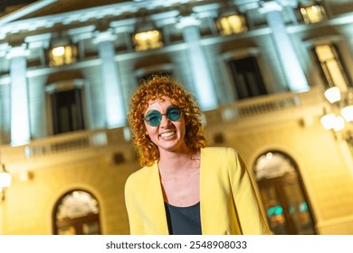 Modern woman in yellow casual clothes and sunglasses laughing at camera standing in the city at night - Powered by Shutterstock