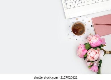 Modern woman's desktop, home office. Computer, cup of coffee and spring flowers on a light table. Minimal business concept, home comfort, top view, flat lay,