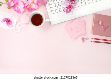 Modern Woman's Desktop, Home Office. A Computer, A Cup Of Tea, A Medical Mask And Spring Flowers On A Light Table. Minimal Business Concept, Home Comfort, Top View, Flat Lay, Space For Text.